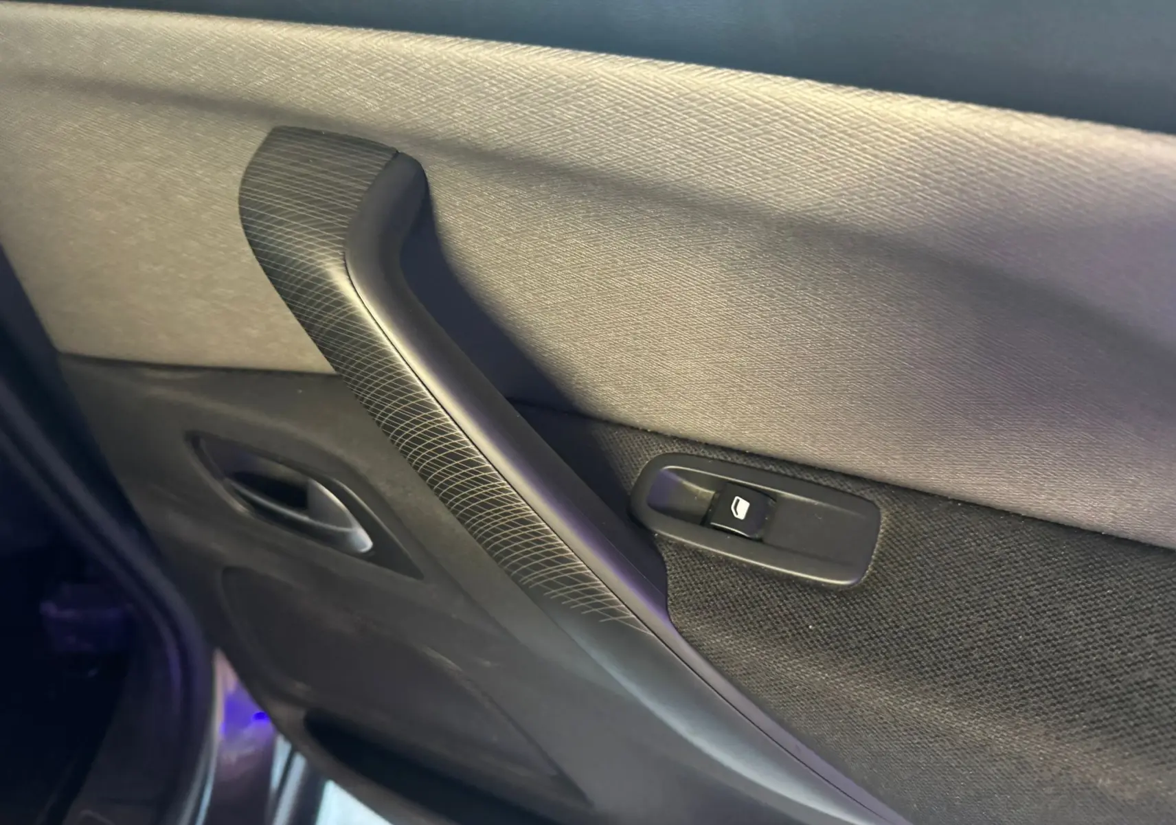 Détail de la poignée intérieure et commande de vitre du côté gauche d’une Citroën C4 Picasso 2016 gris.