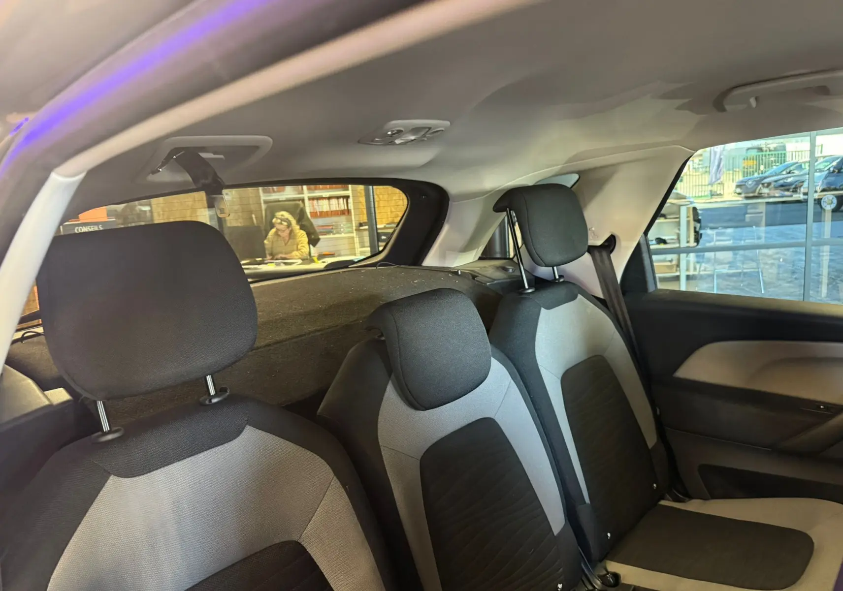 Vue intérieure arrière droite montrant les sièges gris et noirs du Citroën C4 Picasso 2016.