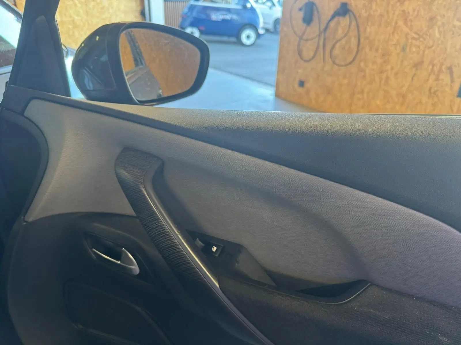 Vue intérieure de la porte côté conducteur de la Citroën C4 Picasso gris, avec poignée noire et bouton de commande vitre.