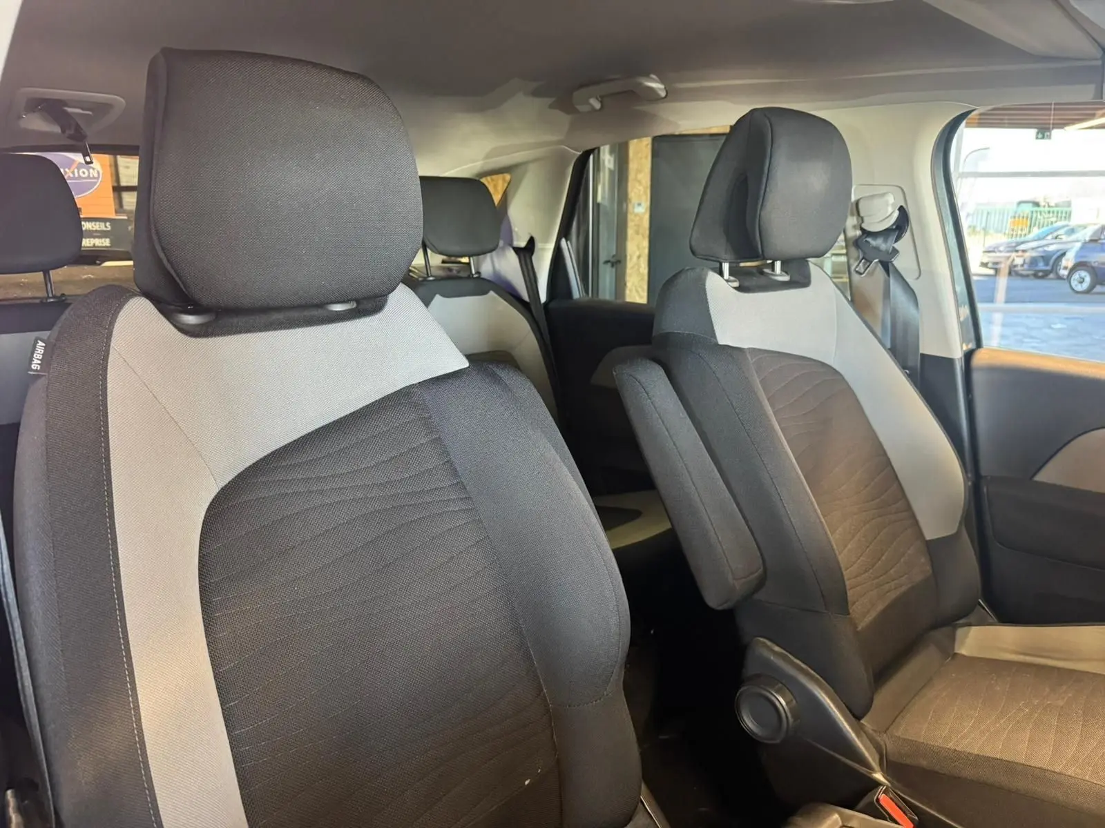 Vue intérieure des sièges avant en tissu noir et gris du Citroën C4 Picasso 2016, côté droit, avec appuie-bras et ceinture visible.