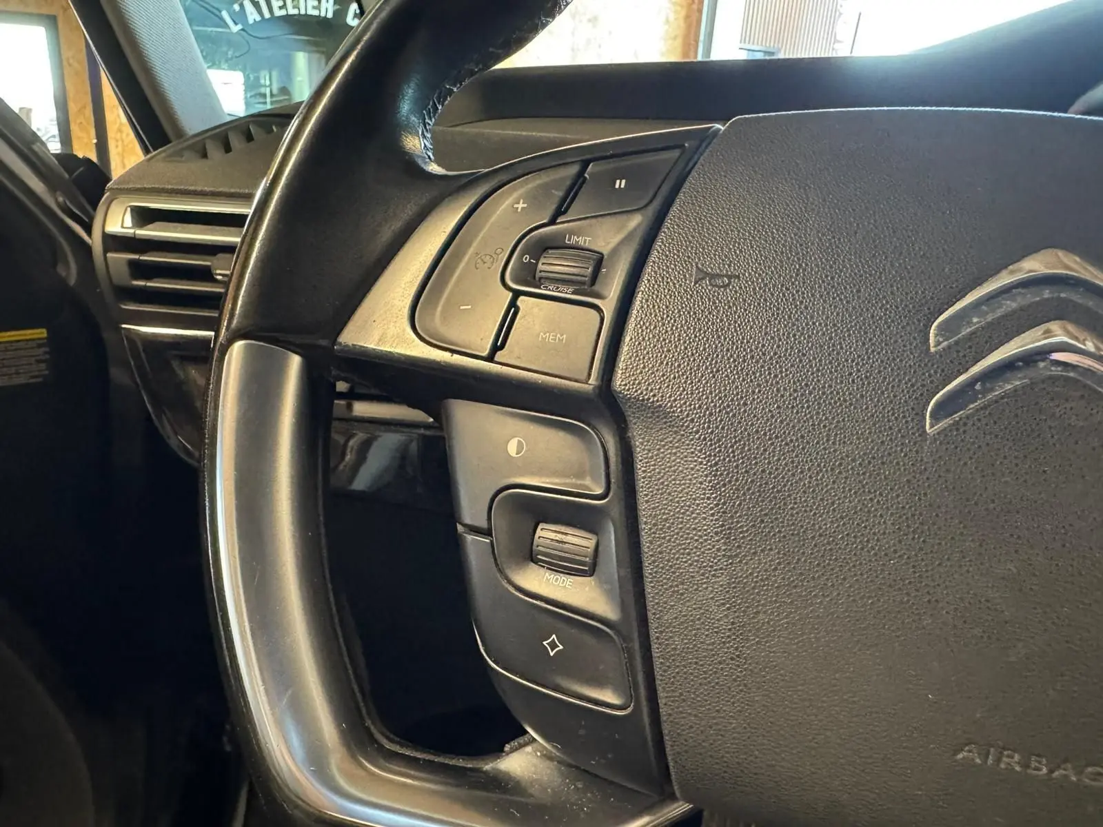 Gros plan sur le volant cuir noir multifonctions de la Citroën C4 Picasso 2016, avec commandes intégrées.