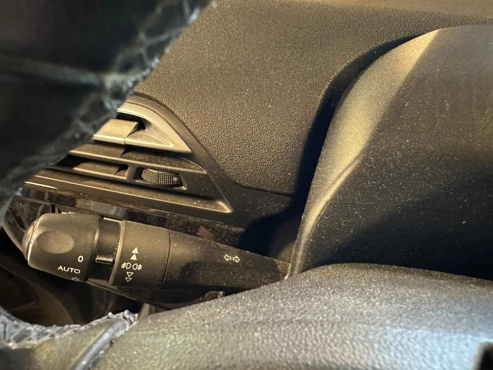 Gros plan sur la commande des feux et clignotants à gauche du volant noir dans l'habitacle du Citroën C4 Picasso gris.