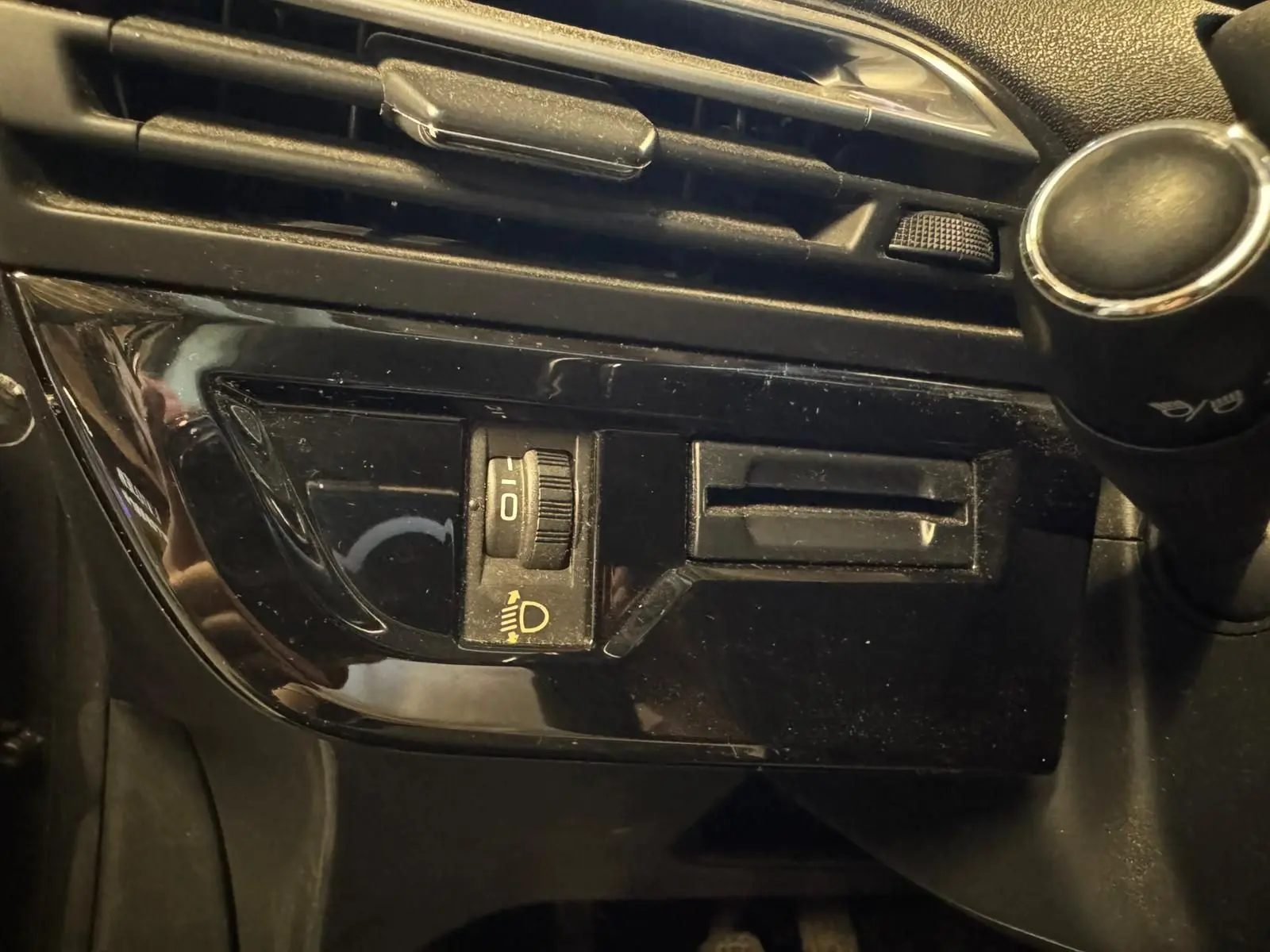 Gros plan sur le tableau de bord noir du Citroën C4 Picasso 2016, montrant la molette de réglage des phares.