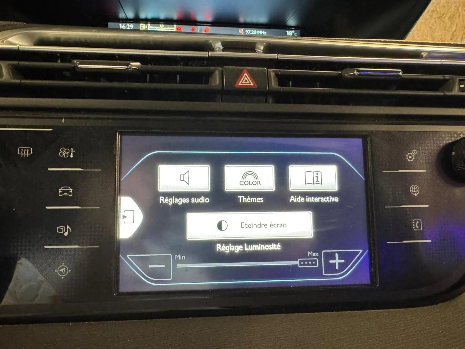 Vue rapprochée de l'écran tactile central du tableau de bord de la Citroën C4 Picasso gris, affichant les réglages audio et luminosité.