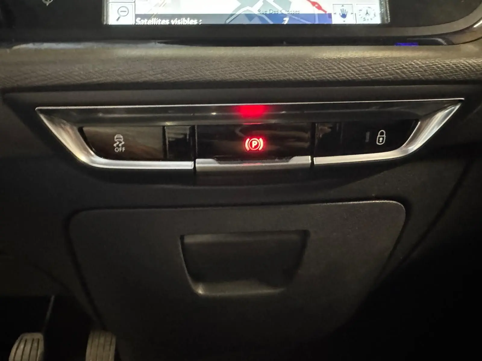Gros plan sur la console centrale noire du Citroën C4 Picasso 2016 avec bouton de frein à main électronique allumé en rouge.
