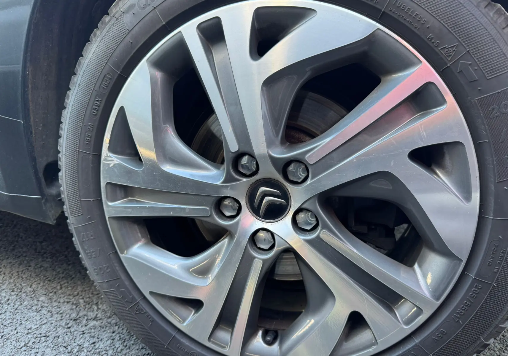 Gros plan sur la jante alu grise d'une Citroën C4 Picasso 2016, mettant en valeur le logo Citroën au centre.