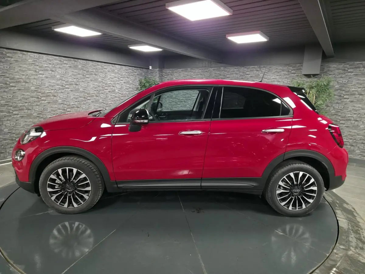 Vue latérale droite d'un Fiat 500X rouge Passione avec jantes alliage 17 pouces et vitres surteintées.