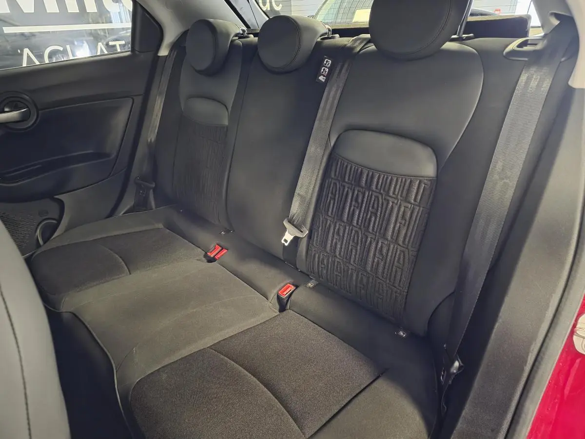 Vue intérieure de la banquette arrière noire avec monogramme FIAT, côté droit du Fiat 500X rouge 2024.