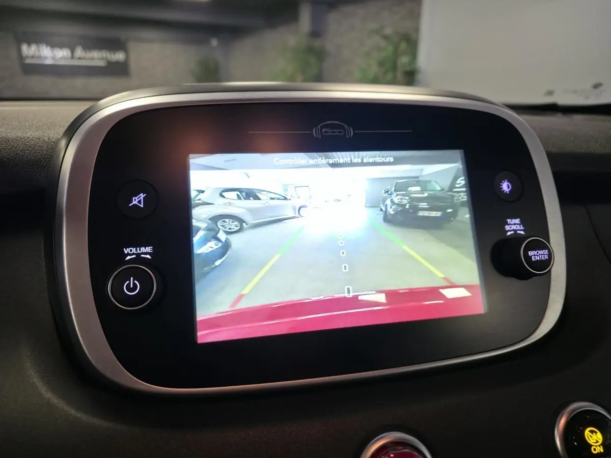 Écran multimédia affichant la caméra de recul d'une Fiat 500X rouge, vue intérieure centrée sur l'écran tactile.
