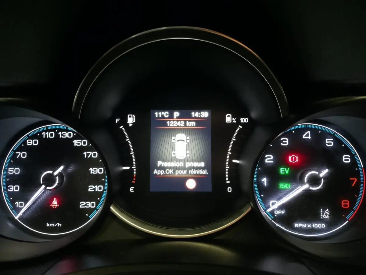 Tableau de bord de Fiat 500X 2024 avec affichage numérique central et compteurs analogiques éclairés en bleu et rouge.