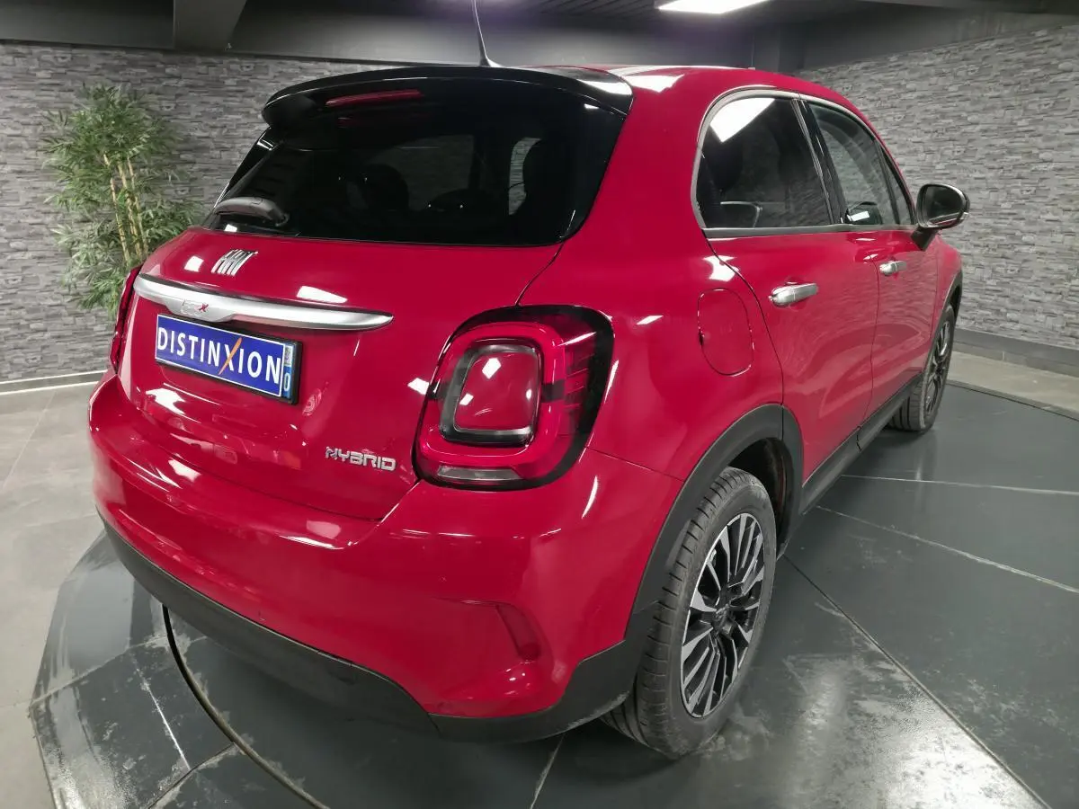Vue 3/4 arrière droite d'une Fiat 500X rouge Passion avec jantes alliage 17'' et vitres surteintées.