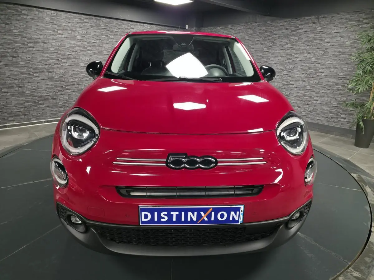 Vue avant d'une Fiat 500X rouge vif avec phares LED ronds et calandre noire dans un showroom.