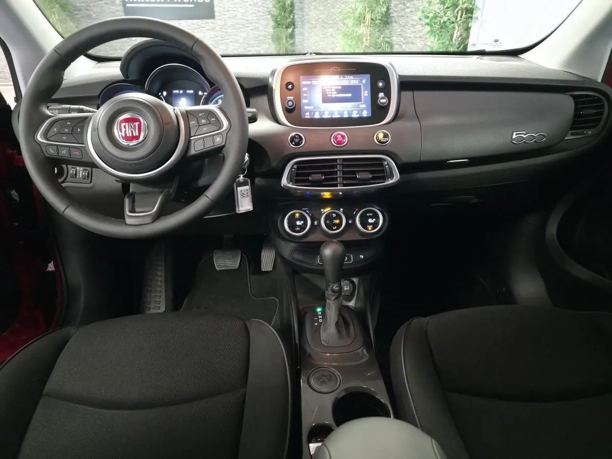 Vue intérieure frontale du tableau de bord du Fiat 500X 2024 avec volant multifonction et écran tactile central.