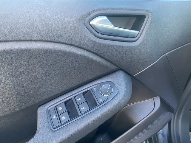 Détail de la porte avant gauche gris foncé de la Renault Clio 2025 avec commandes électriques des vitres et poignée argentée.
