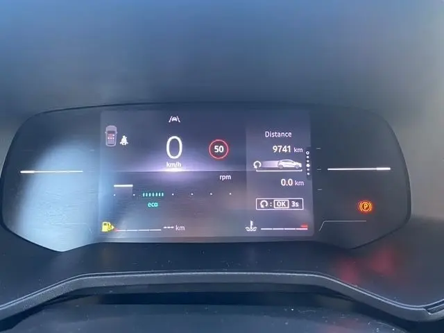 Gros plan sur le combiné d'instruments numérique de la Renault Clio gris foncé, affichant la vitesse, la distance et les alertes.