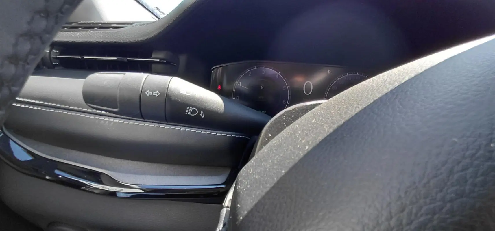 Gros plan sur le commodo de clignotants et phares du tableau de bord noir du Jeep Compass 2025.