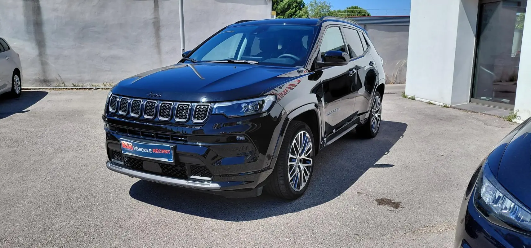 Jeep Compass noir en 3/4 avant droit avec jantes alliage 19 pouces et barres de toit visibles en extérieur.