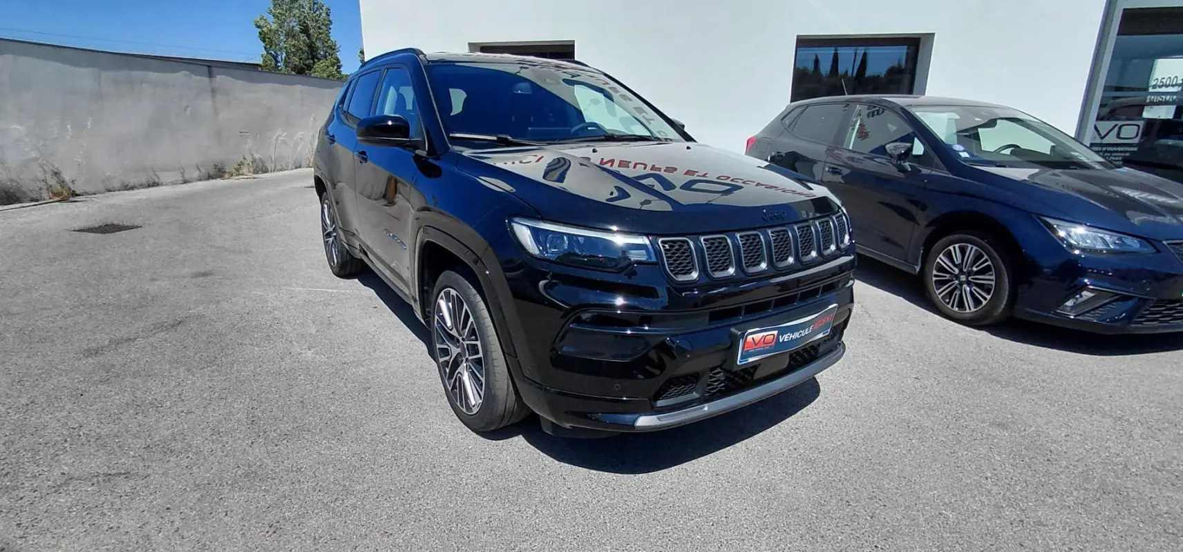 Jeep Compass noir vu en 3/4 avant droit, avec jantes alliage 19 pouces et barres de toit visibles.