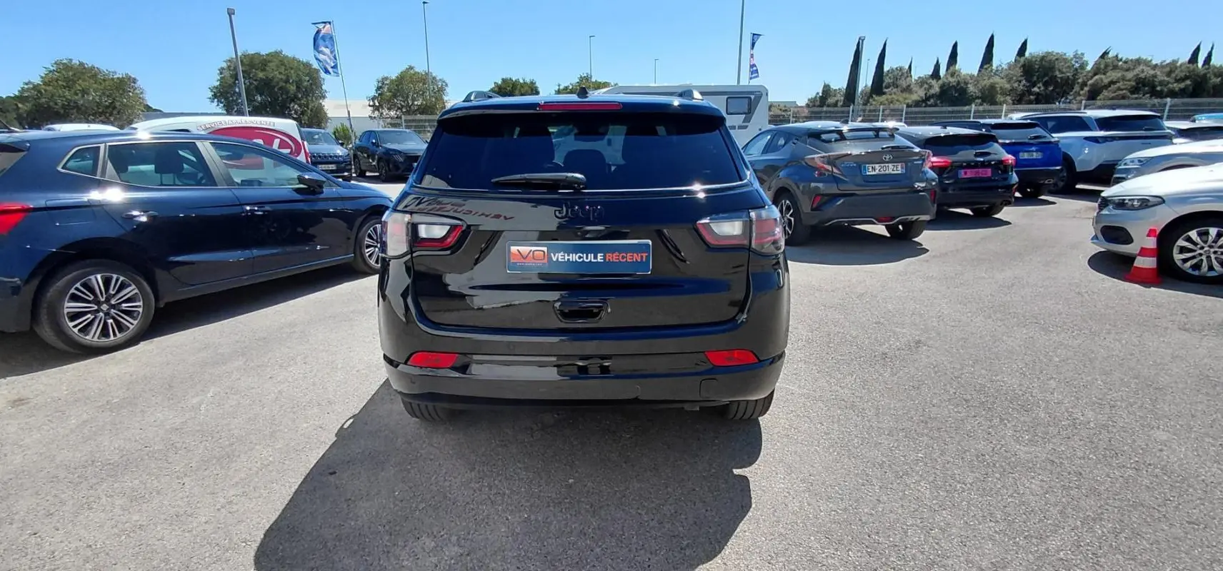 Vue arrière d'un Jeep Compass noir 2025 avec barres de toit et jantes alliage 19 pouces, stationné en extérieur.
