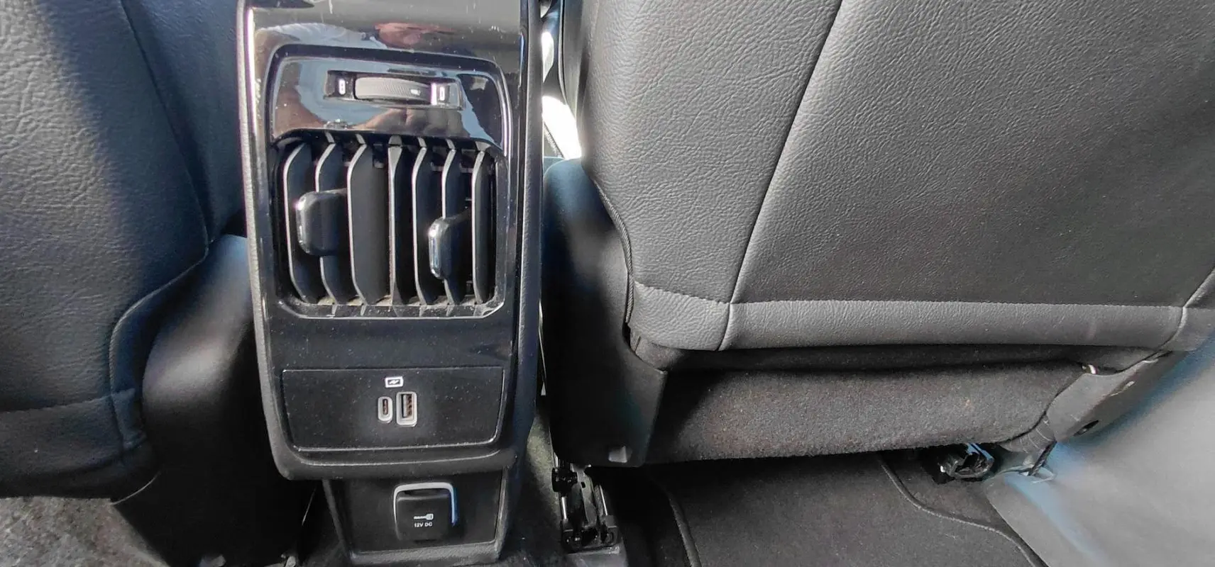 Vue rapprochée de la console arrière noire du Jeep Compass 2025 avec prises USB, prise 12V et aérateurs.