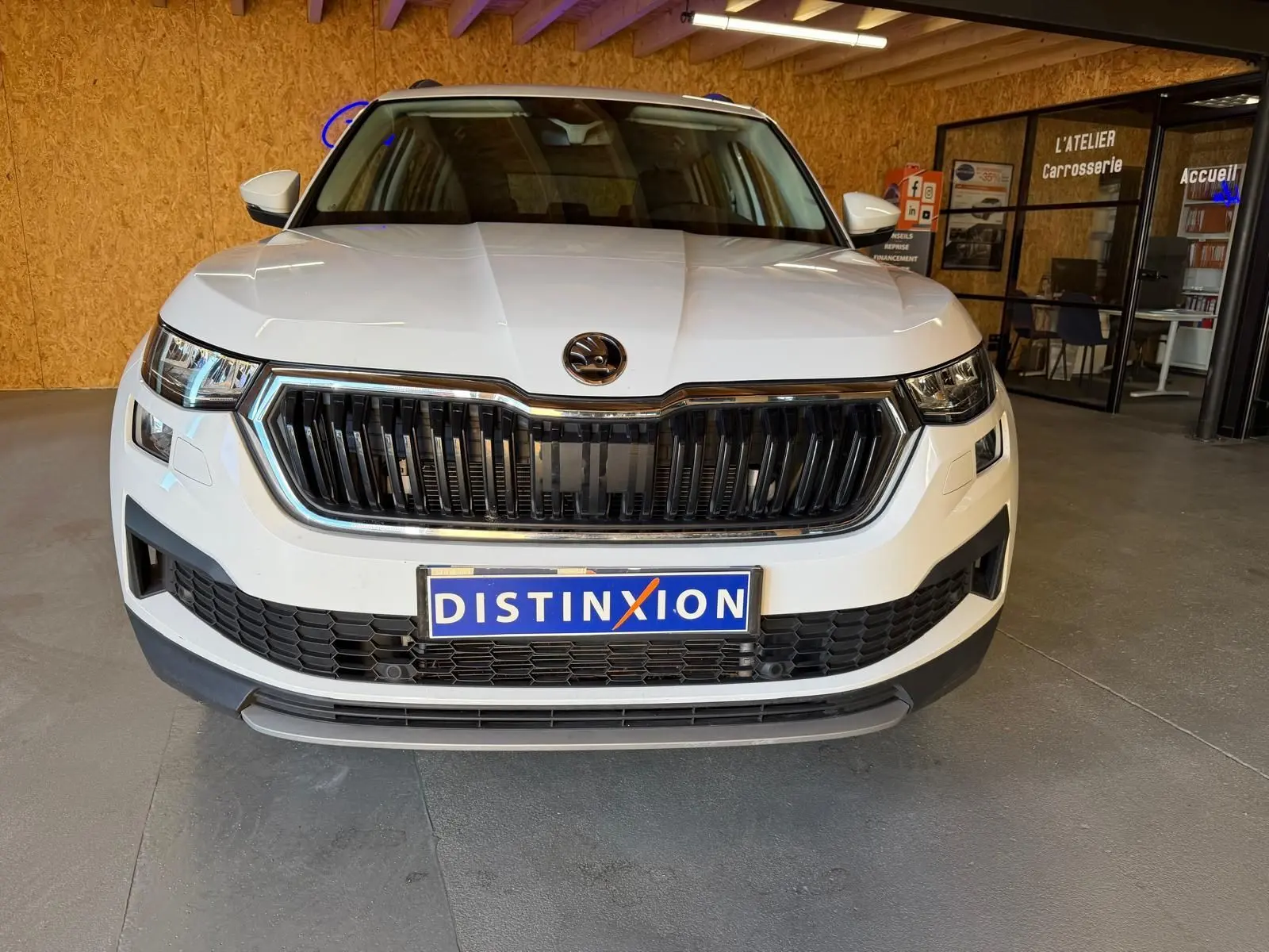 Vue 3/4 avant droite d'un Skoda Kodiaq blanc 2023 avec calandre chromée et phares LED distinctifs.