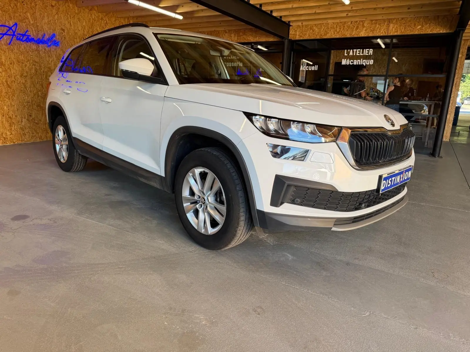 Vue 3/4 arrière droite d'un Skoda Kodiaq blanc 2023, SUV 7 places avec feux arrière LED et toit noir.
