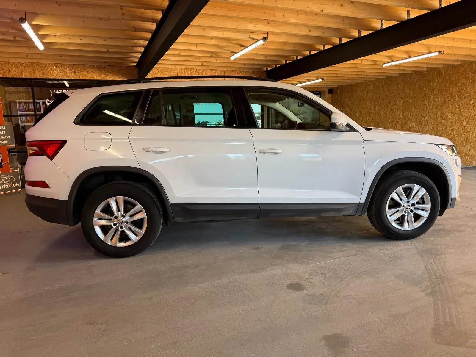 Vue 3/4 arrière droite d'un Skoda Kodiaq blanc 2023 avec toit noir et jantes en alliage, sur fond neutre.