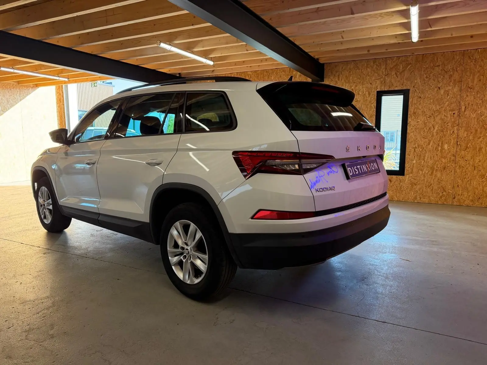 Vue intérieure côté gauche du Skoda Kodiaq blanc 2023, sièges avant en tissu noir et tableau de bord moderne.