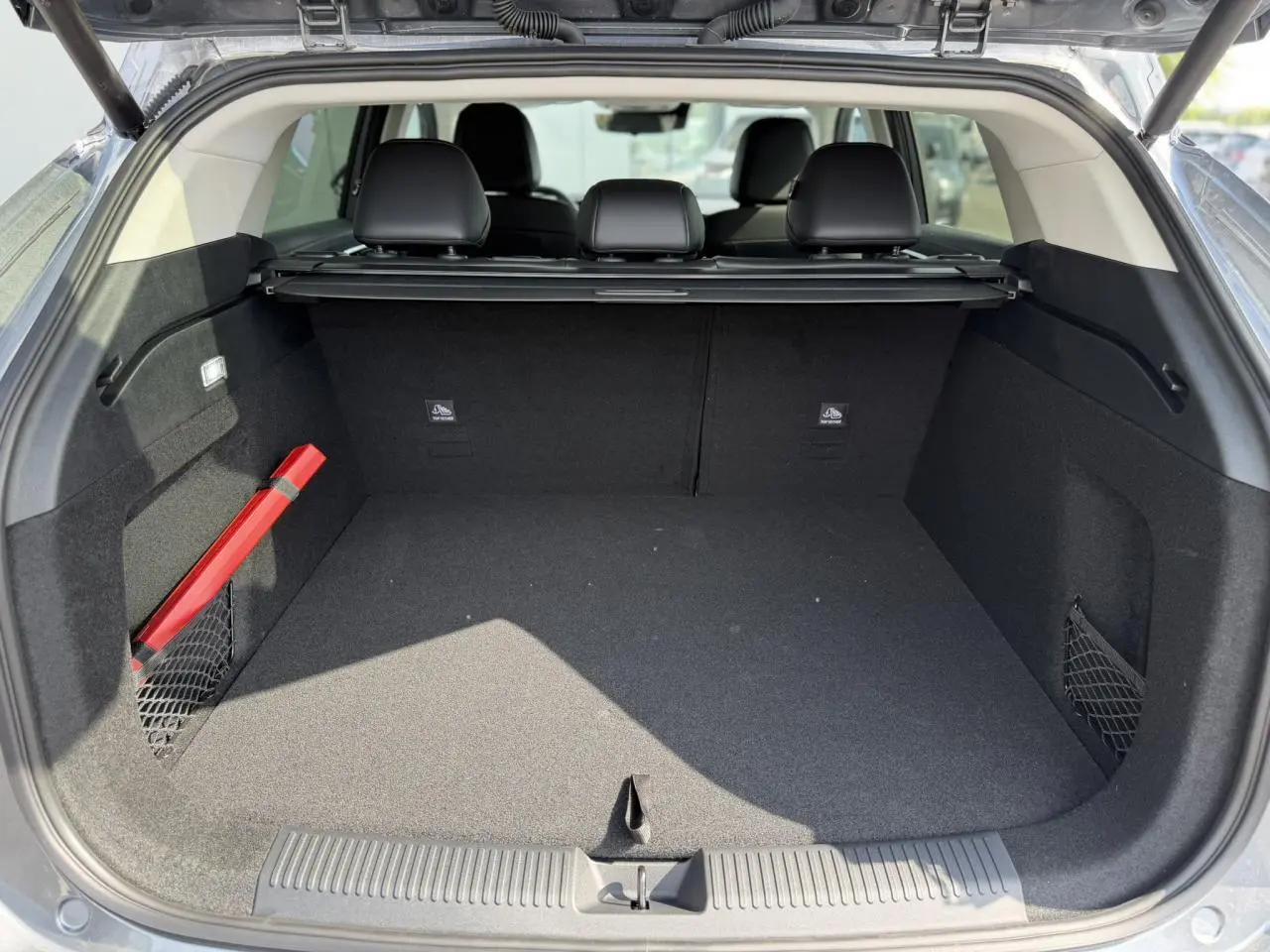 Coffre ouvert vu de l'arrière d'un MG MOTOR EHS gris, montrant un espace de chargement propre avec filet latéral et triangle de sécurité rouge.