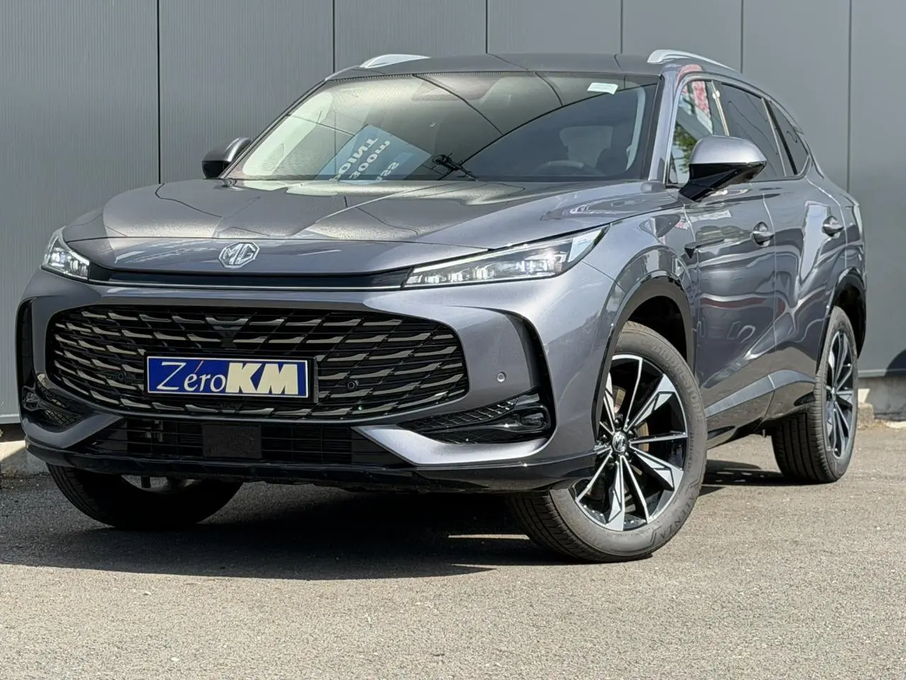 MG Motor EHS 1.5 Hybrid+ gris métallisé vu en 3/4 avant droit avec calandre noire et jantes alliage 19 pouces.