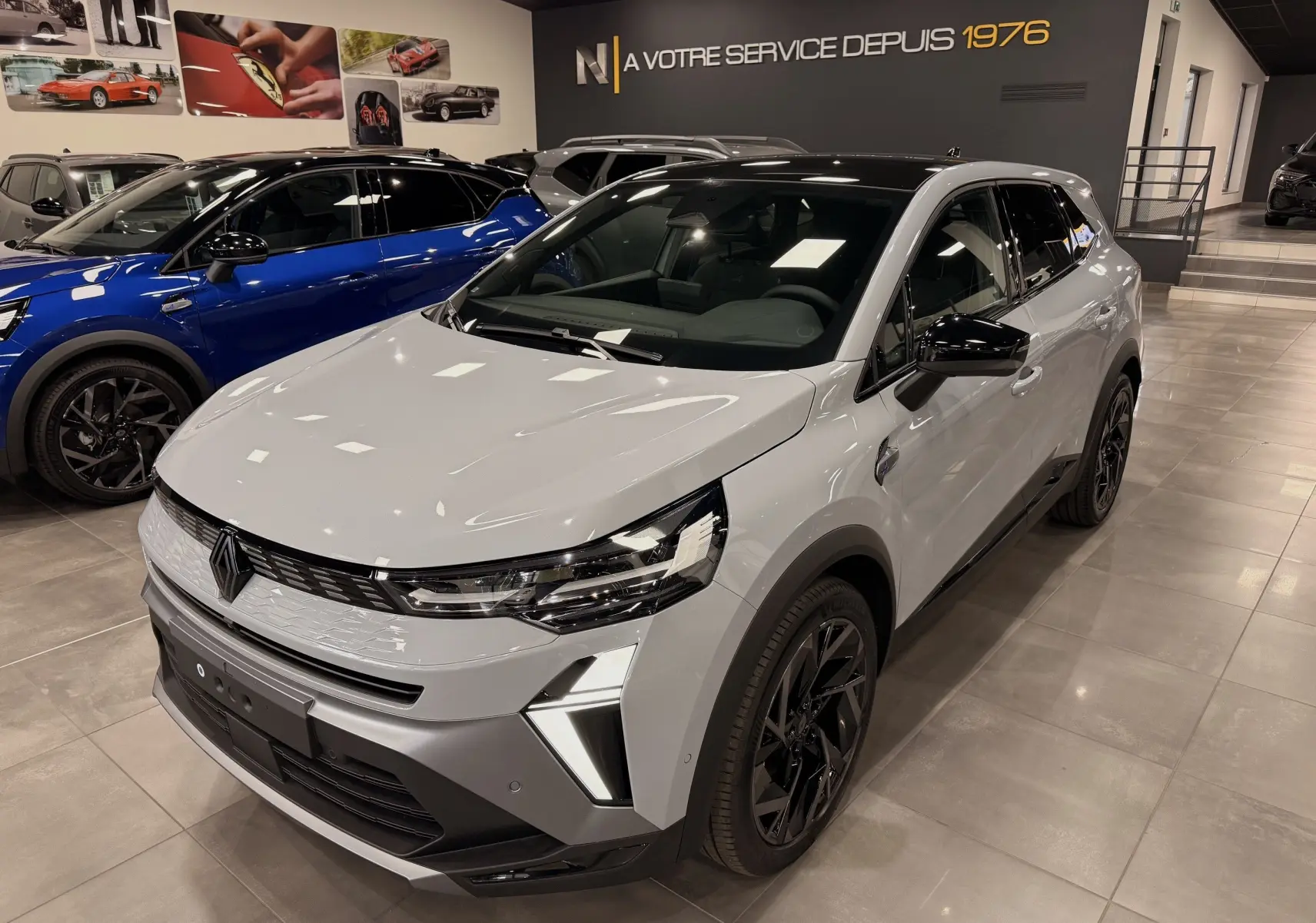 Renault SYMBIOZ gris Rafale en 3/4 avant droit, avec jantes noires et éclairage LED distinctif en showroom.
