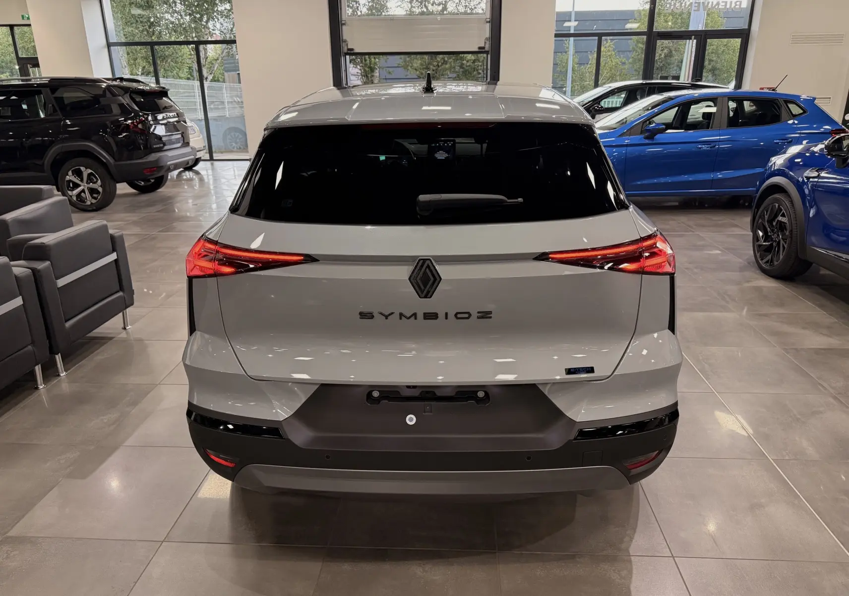 Vue arrière du Renault SYMBIOZ gris Rafale en showroom, mettant en valeur ses feux LED fins et son design épuré.