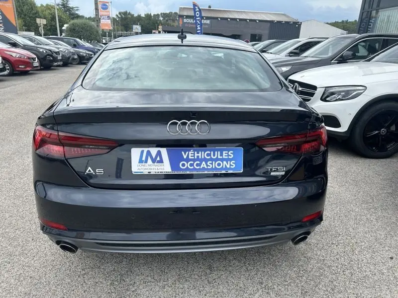 Vue arrière d'une Audi A5 Sportback bleu lunaire métal, avec feux LED et double sortie d'échappement visible.
