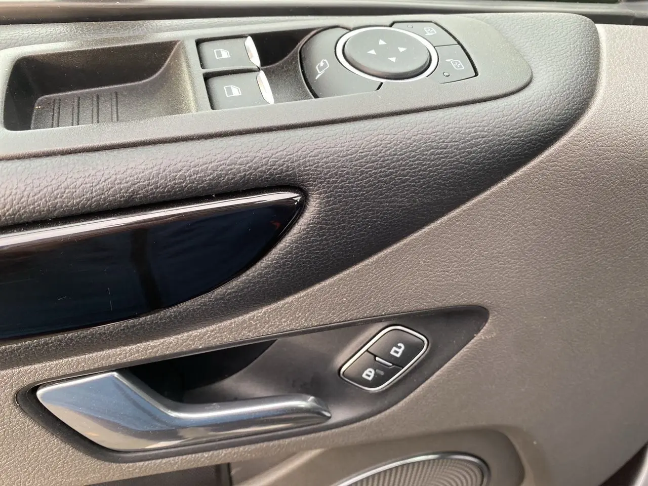Gros plan sur la poignée intérieure côté gauche en plastique gris et les commandes de vitres du Ford Tourneo Custom 2020.