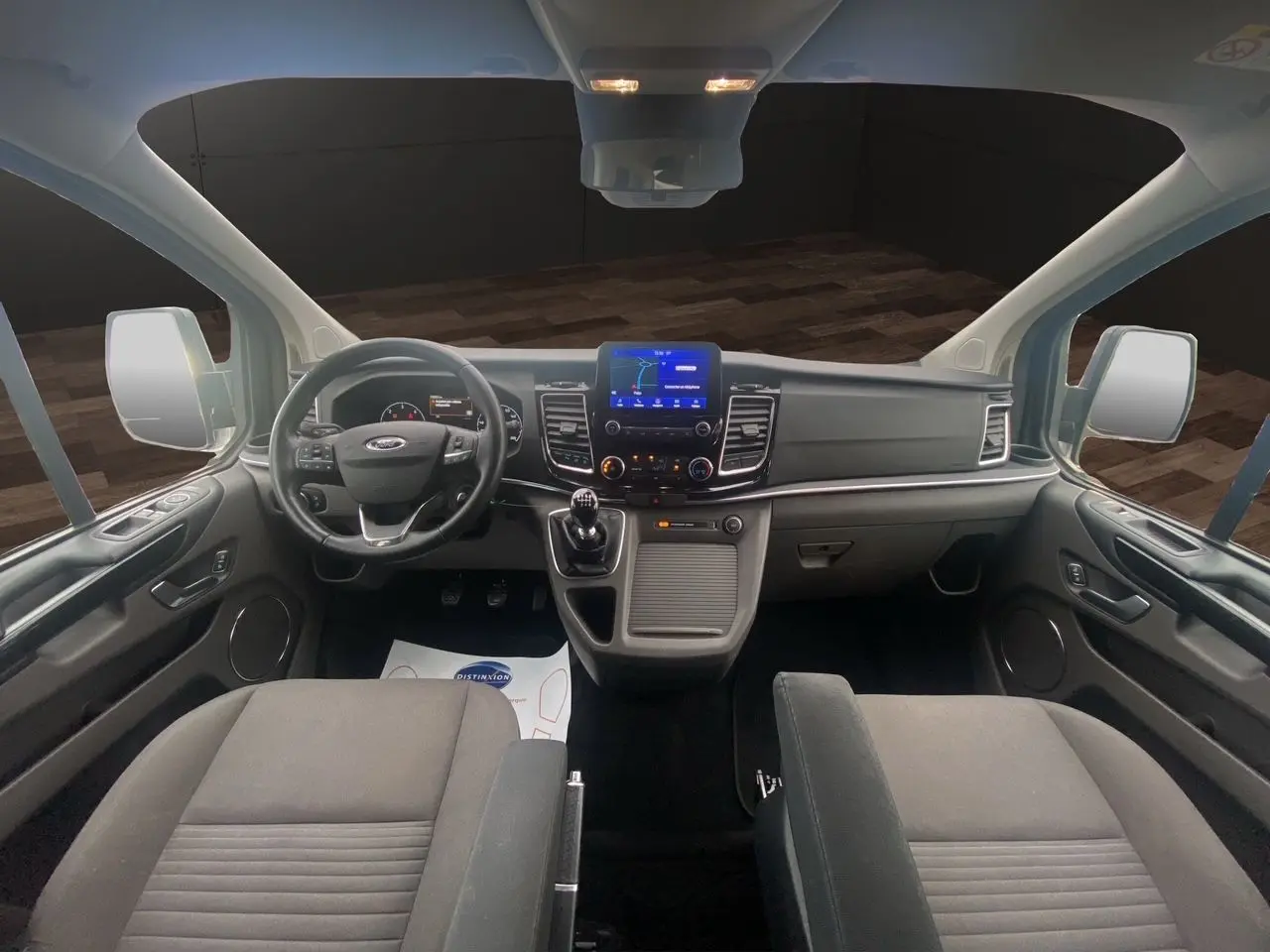 Vue intérieure frontale du Ford Tourneo Custom 2020 avec tableau de bord moderne et sièges noirs en tissu.