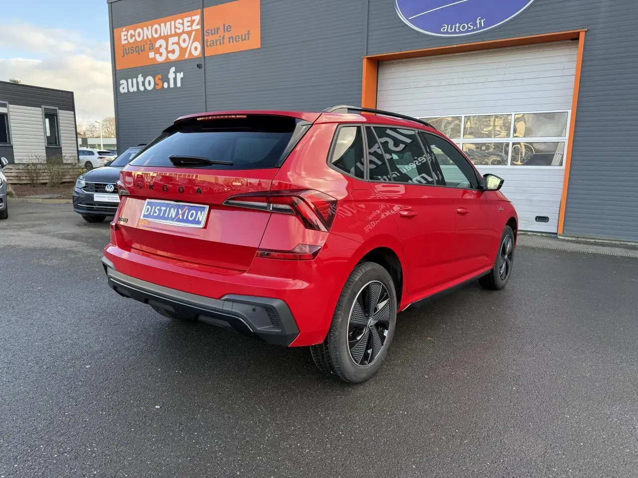 Vue 3/4 arrière droite d'un Skoda Kamiq 1.5 TSI Monte-Carlo rouge velvet métallisé avec jantes noires et vitres surteintées.