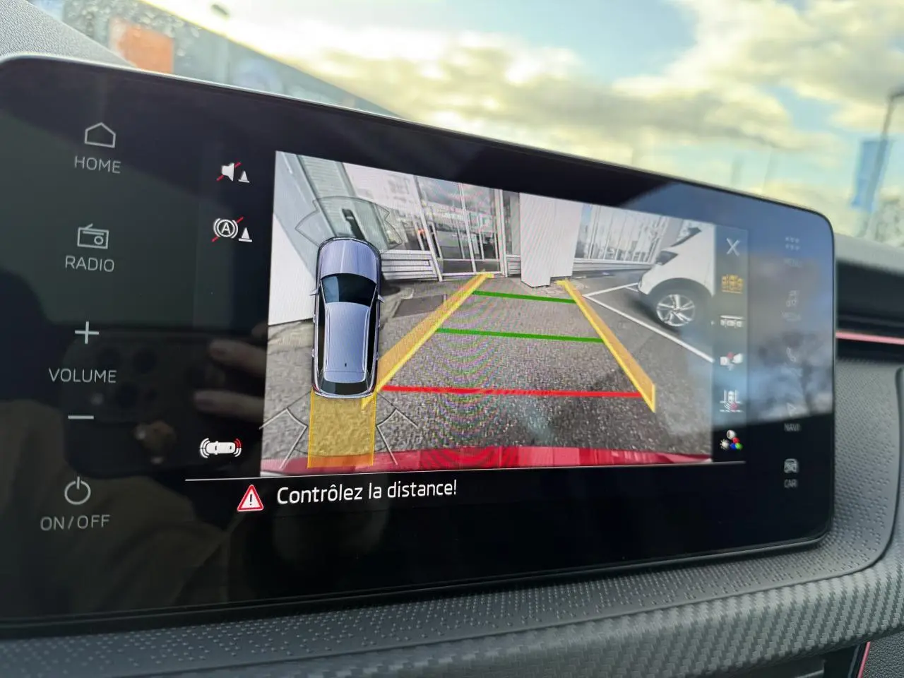 Écran tactile intérieur affichant la caméra de recul du Skoda Kamiq rouge Velvet, avec lignes de guidage colorées.