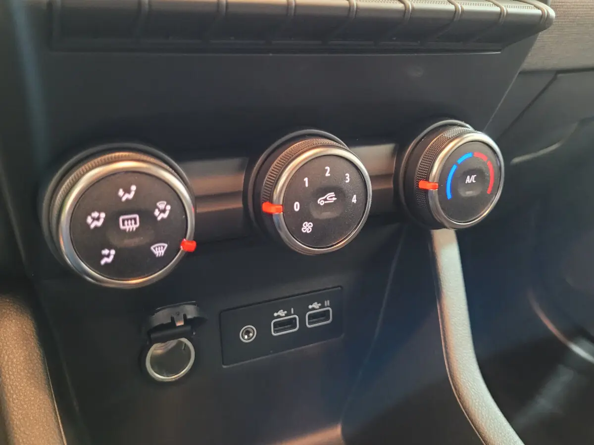 Gros plan sur les commandes de climatisation et les ports USB de la Renault Clio Evolution Blue dCi 100, tableau de bord noir.