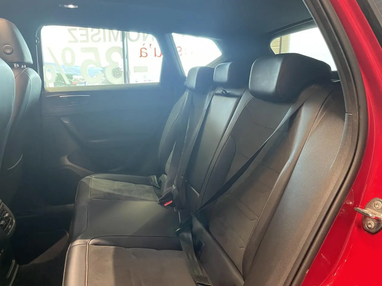 Vue intérieure côté droit des sièges arrière en cuir noir du SEAT Ateca rouge 2022, avec ceinture de sécurité attachée.
