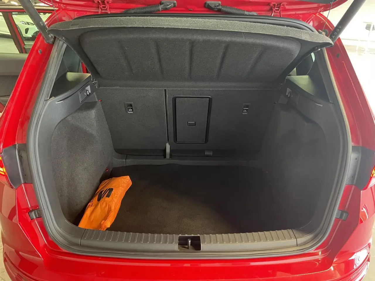 Coffre ouvert vu de l'arrière d'un SEAT Ateca rouge 2022, avec un sac orange à l'intérieur.