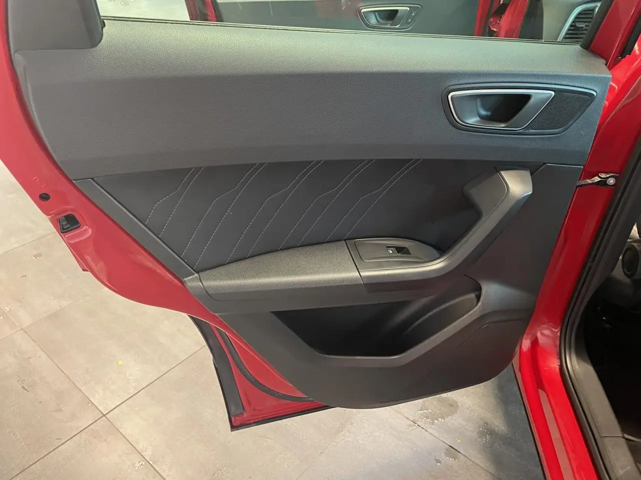 Vue rapprochée de la porte arrière gauche rouge du SEAT Ateca 2022, avec garniture noire et bouton de vitre électrique.