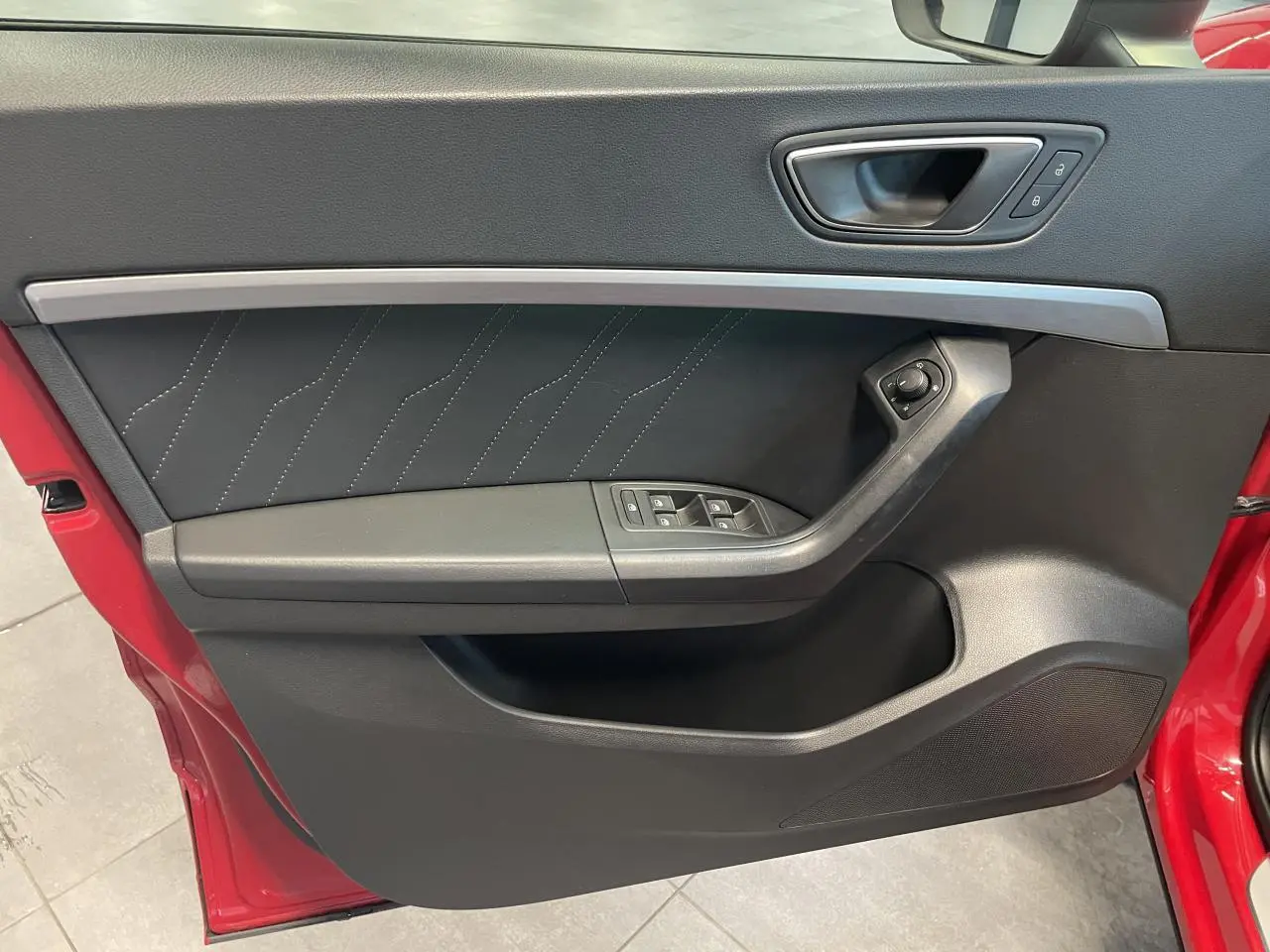 Détail de la porte côté conducteur du SEAT Ateca rouge 2022, montrant les commandes de vitres et la poignée intérieure.