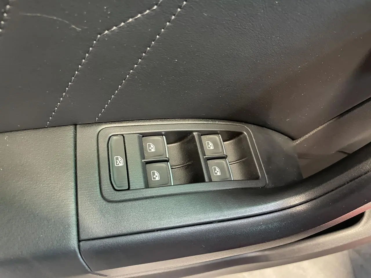 Commande des vitres électriques sur la portière intérieure noire du SEAT Ateca rouge, vue en gros plan.