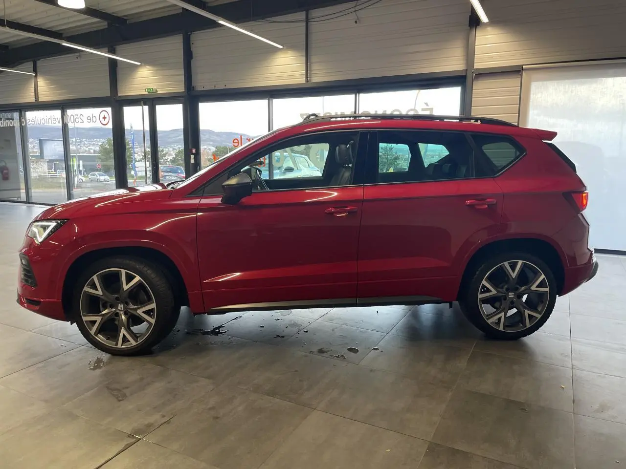 Vue de profil côté gauche d’un SEAT Ateca rouge 2022 en version FR, avec jantes alliage et toit ouvrant visible.