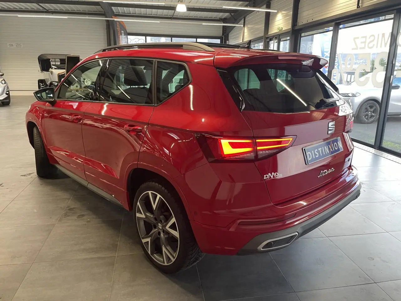 Vue 3/4 arrière droite d'un SEAT Ateca rouge 2022 avec feux allumés et jantes alliage distinctives en concession.