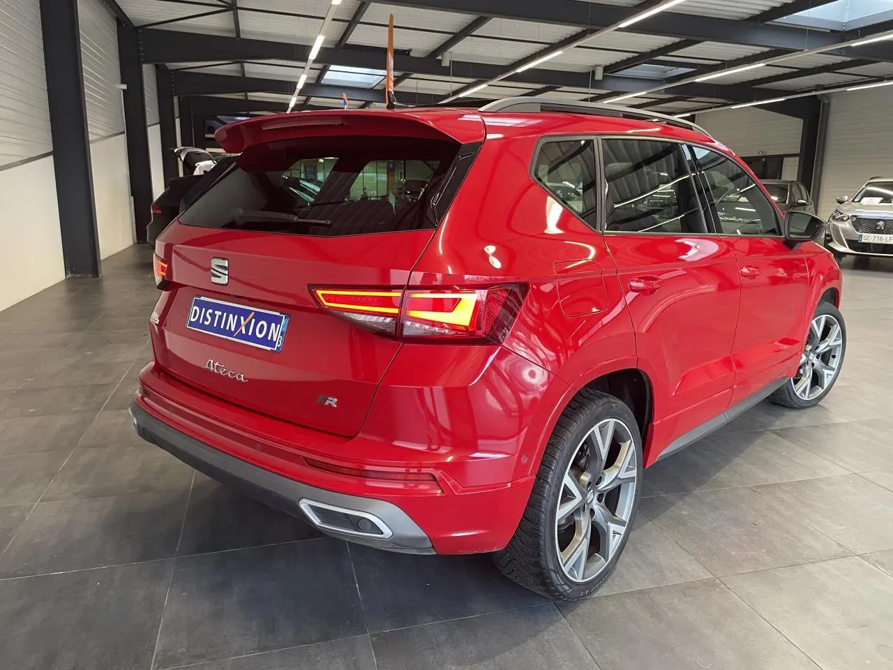 Vue 3/4 arrière droite d'un SEAT Ateca rouge 2022, version FR avec feux allumés et jantes alliage distinctives.