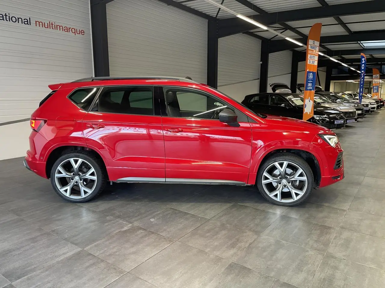 Vue de profil côté gauche d'un SEAT Ateca rouge 2022 version 2.0 TDI FR avec jantes alliage en concession.