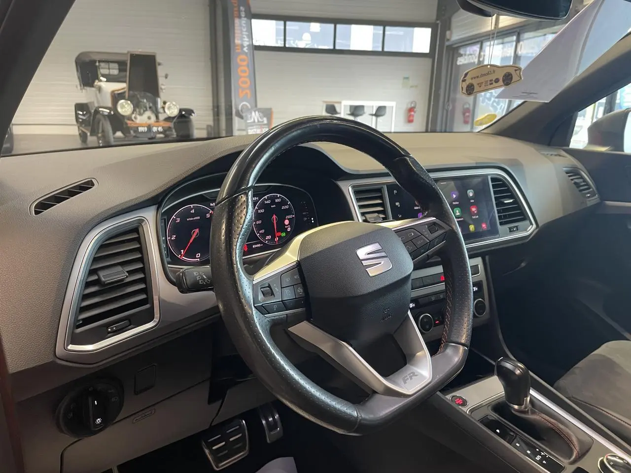 Vue intérieure du poste de conduite du SEAT Ateca rouge 2022, volant cuir avec logo FR et tableau de bord digital.