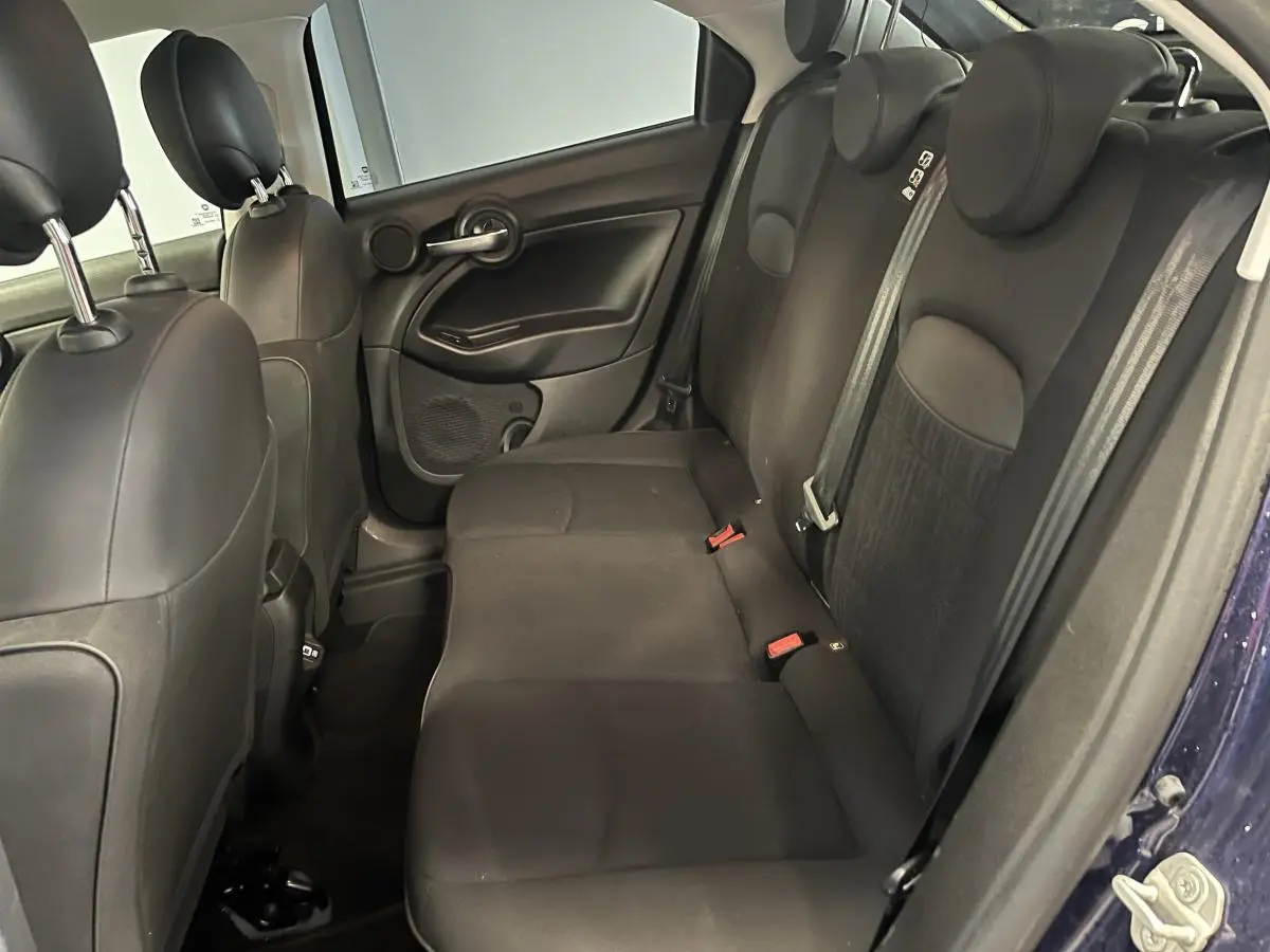 Vue intérieure côté droit des sièges arrière noirs du Fiat 500X 2024 avec appuie-têtes et ceintures visibles.