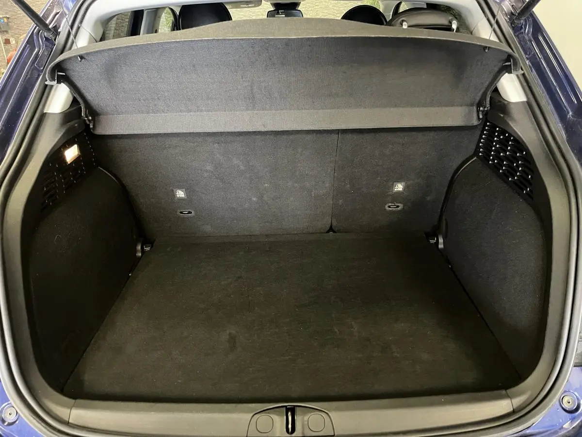 Coffre ouvert vu de l'arrière d'une Fiat 500X bleu, montrant l'espace de rangement et la plage arrière noire.